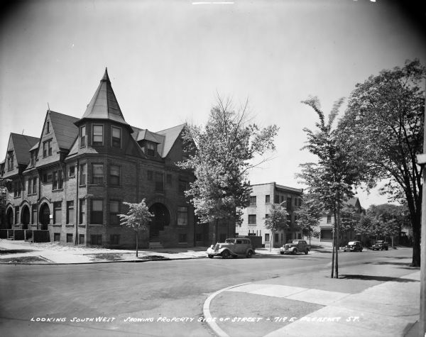 Residential neighborhood with cars parked on the street, located at N. Cass and E. Pleasant Streets, looking southwest. Caption on glass plate reads: "Looking southwest showing property side of street, 719 E. Pleasant Street".