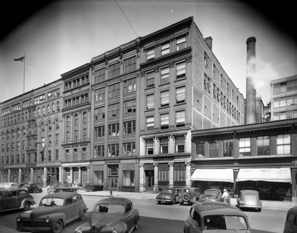 Kolmar laboratories, a cosmetic manufacturer, is housed in the six-story building with the white facade. Northwestern Extract Company, supplier of beverage flavoring, is located in the two-story building to the right with the awnings. There is a U.S. Army Recruiting and Induction Station on the left. All are located on the east side of Broadway between E. Chicago and E. Buffalo Streets.
