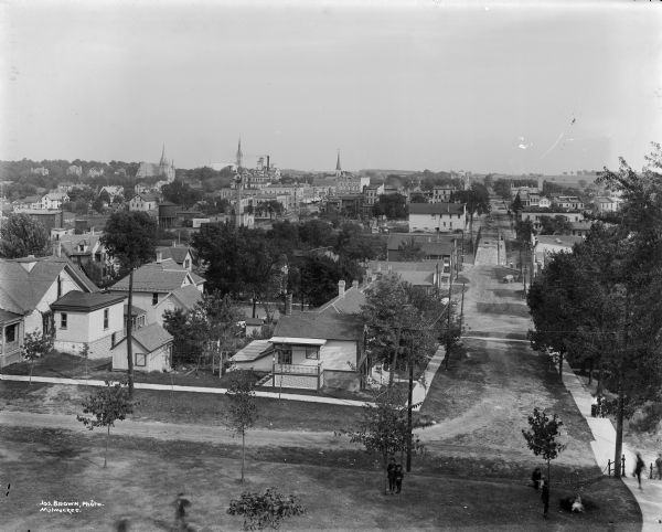 Elevated view of the town, probably from the west bank of the Rock River. Pedestrians are walking through a park in the foreground.