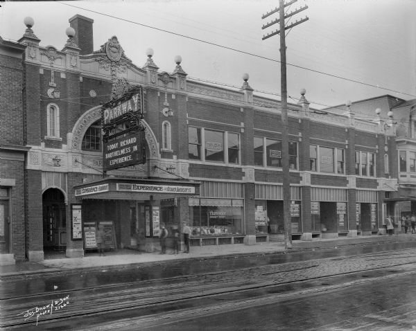 Parkway Theater, 3417 W. Lisbon Avenue. Individuals are walking on sidewalk in front of the buildings.
