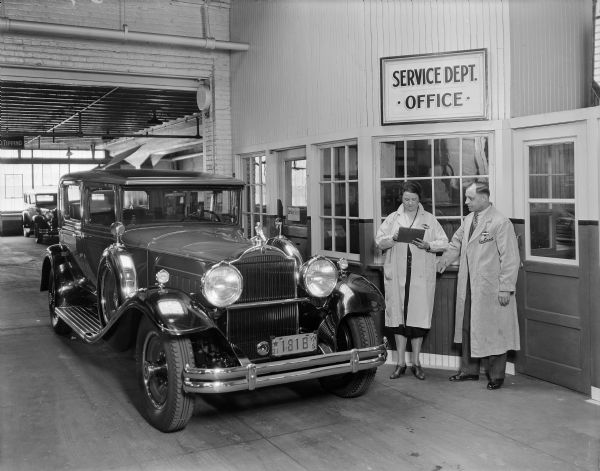 Two employees of Packard Auto in front of the service department office with automobile.