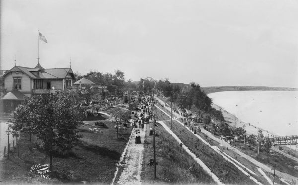 Elevated view of Pabst Whitefish Bay Resort on the shores of Lake Michigan, with crowds of individuals walking up the numerous paths that lead to the resort's entrance.