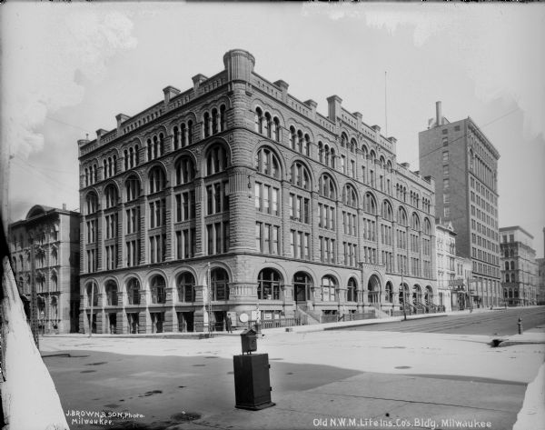 Northwestern Mutual Life Insurance Building and surrounding commercial area on the northwest corner of Broadway and E. Michigan Streets. Caption on glass plate reads: "Old N.W.M. Ins. Co's Bldg."