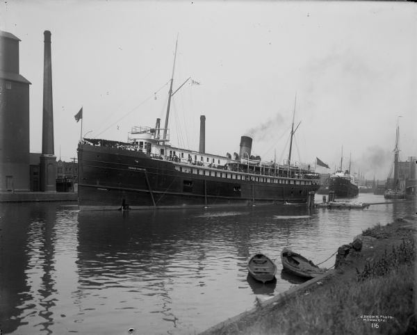 View of two steamboats, looking up the Milwaukee River from the north bank, near the foot of N. Milwaukee Street. Both steamboats are of the Goodrich Transportation Company. The boat in the foreground is named "Virginia".