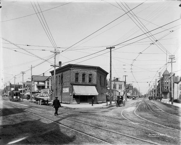 Looking northwest on Fond du Lac Avenue from W. Walnut Street. In the center is a building with awning that reads: "1220 Zautcke Bros." Streetcars, pedestrians and horse-drawn vehicles are on the surrounding streets. A Post Office is on the far right.