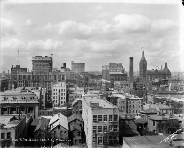Looking west from the roof of the Northwestern Mutual home office at E. Wisconsin Avenue and N. Van Buren Street. City Hall is on the right. Caption on glass plate reads: "View W. from N.W.M.L.I. Co's Building". The top of the Pfister Hotel is on the left side.