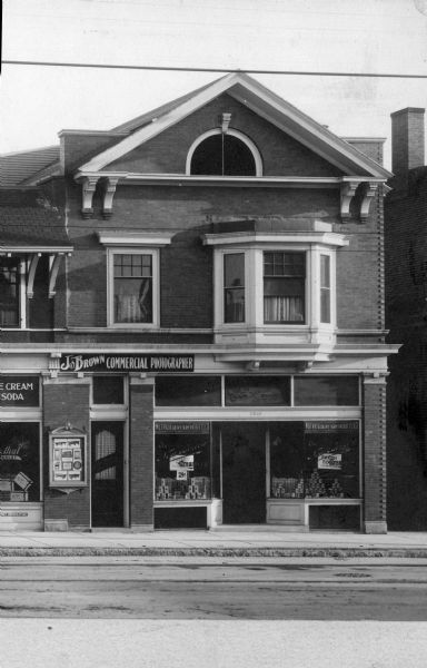 Exterior view across street of Joseph Brown's photography studio at 3803 West Lisbon Avenue. A sign on the building reads: "Joseph Brown Commercial Photographer."