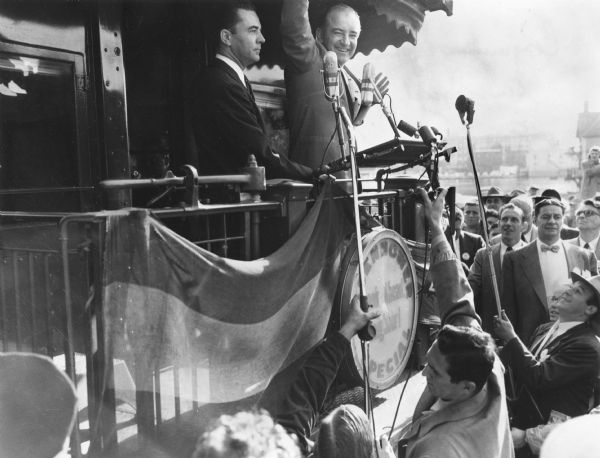 Senator Joseph R. McCarthy waves to the crowd who had come to see him introduce Presidential candidate Dwight Eisenhower.  On the train with him is John Byrnes, Republican congressman from Green Bay.