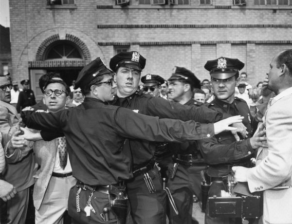 Tensions ran high among the crowd that gathered outside the Brooklyn building where the funeral service for executed Russian spies Julius and Ethel Rosenberg was held. Here the police had to break up a fight that broke out between Rosenberg supporters and members of the press.  Public attitudes toward the Rosenbergs was created in part by Senator Joseph R. McCarthy; at the same time their trial and conviction lent credence to his charges.