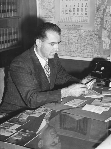Joseph R. McCarthy opens congratulatory telegrams after his primary election victory over Senator Robert M. La Follette, Jr., a victory which ended the La Follette's hold on the Wisconsin Senate seat since 1906. McCarthy is pictured in his office as circuit court judge.