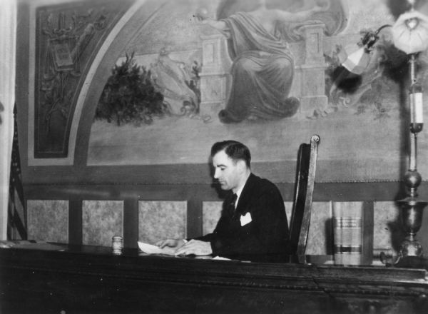 Judge Joseph R. McCarthy sitting at the bench at the Outagamie Courthouse. This photograph was featured in McCarthy's U.S. Senate campaign literature in 1946 along with a caption concerning his ability to cut red tape and streamline operations of his circuit.