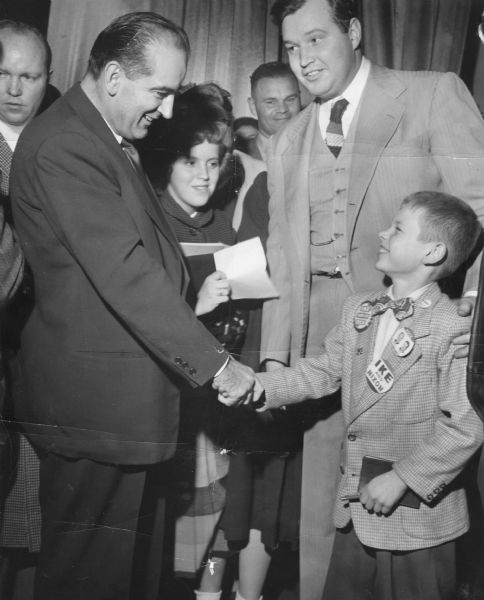 Senator Joseph R. McCarthy of Wisconsin greets his nephew, Kelly Kornely, at a Republican campaign event in Wisconsin.  Also with McCarthy is Assemblyman Gerald Lorge.  Lorge was elected to the Legislature in 1950 while still a college student.  As a representative of Outagamie County (the home of Senator McCarthy), he was also a strong supporter of the Senator.  Lorge served in the state senate from 1954 to 1984.