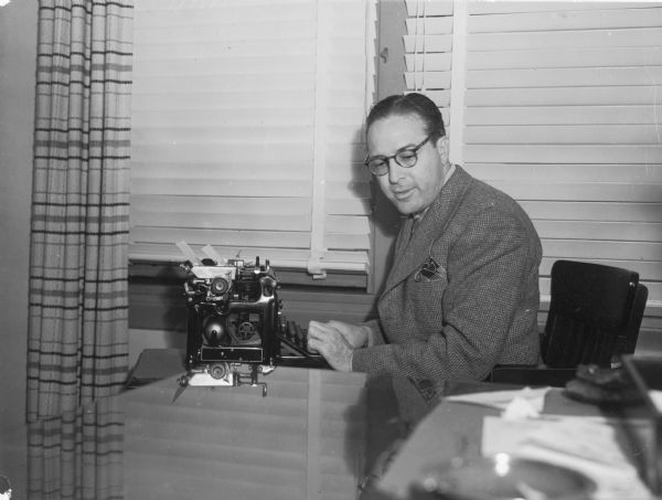 Screenwriter Dalton Trumbo, seated at a typewriter.