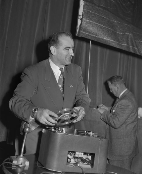 Senator Joseph R. McCarthy prepares to play a tape recording at a dinner honoring him. McCarthy said the tape caught Harry Bridges speaking about plotting to wreck the nation's war effort at a New York meeting on October 11. However, the tape was barely audible.