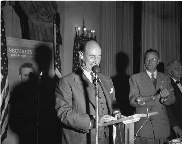 Adlai Stevenson, Democratic Presidential candidate, at a podium speaking to an audience.  To Stevenson's right is Thomas Fairchild, the Democratic candidate running against Senator Joseph  R. McCarthy, and William T. Evjue.