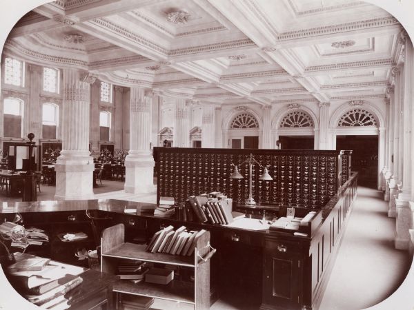 View of the Wisconsin Historical Society Library from the University Library's delivery area, showing the coffered ceiling and the mahogany card catalog. At the time students were not admitted to the stacks.  Instead they filled out call slips and picked up their books at the delivery desk.