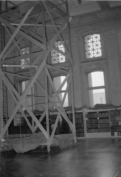 Scaffolding in the Wisconsin Historical Society Library Reading Room constructed for the replacement of the glass skylights and original light fixtures. One of the original light fixtures can be seen.