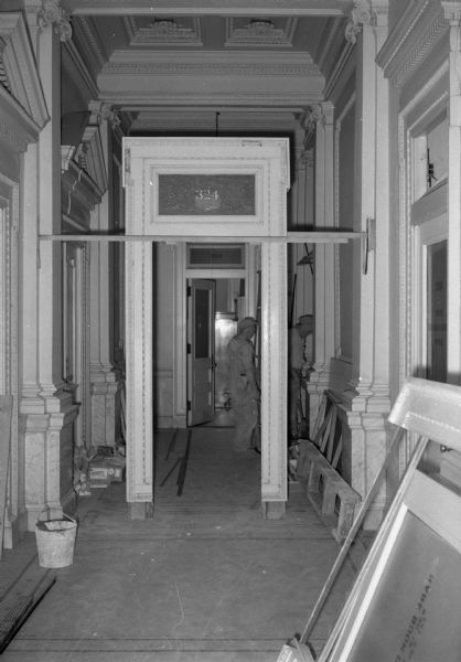 Construction in the corridor in the second floor administrative wing to create a new reception area in the Wisconsin Historical Society.  The photograph shows a doorway from the 3rd floor being installed to create this space.  This photograph provides the best view of the original appearance of the corridor.