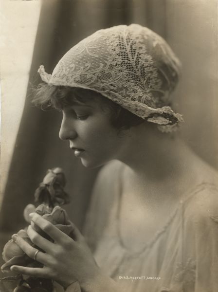 Publicity portrait of the dancer Irene Castle wearing a lace cap and holding a rose, by the Moffett Studio of Chicago.