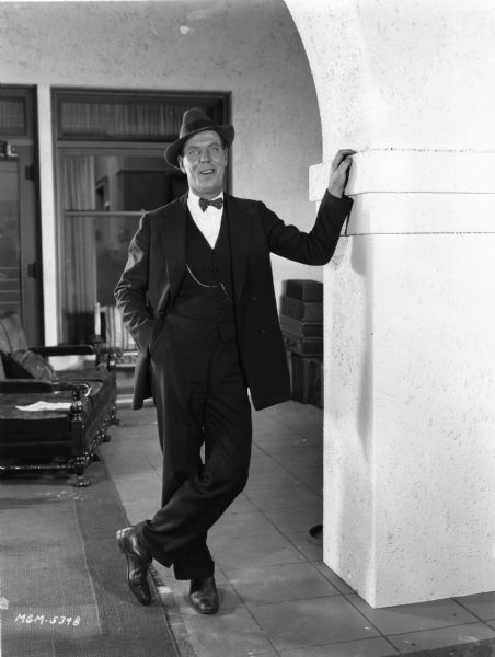 Publicity portrait of Karl Dane standing in what looks like a home.