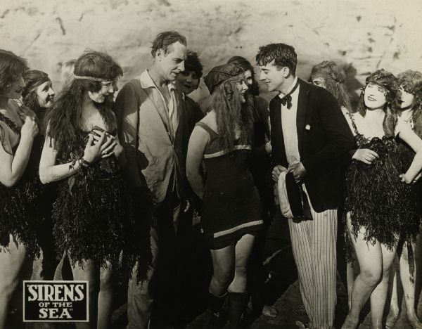 Jack Mulhall and Louise Lovely meet on a beach surrounded by young women wearing bathing costumes composed mostly of seaweed in "Sirens of the Sea" (Universal, 1917).