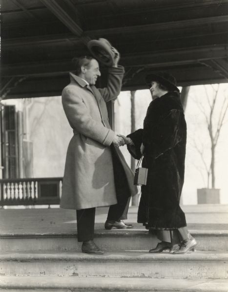 Director D. W. Griffith greets actress Mae Marsh by tipping his hat.