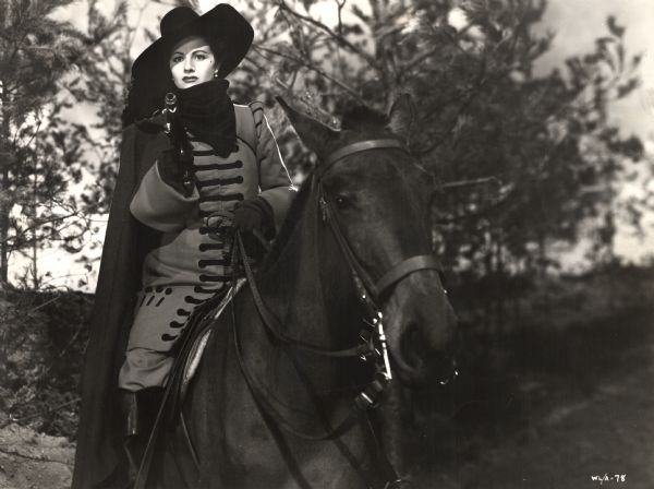 Margaret Lockwood with pistol drawn and sitting on a horse. She stars as Barbara Worth in the 1945 Gainesborough film <i>The Wicked Lady</i>. The costume designer was Elizabeth Haffenden.