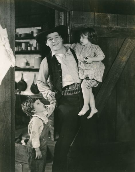 Scene still from <i>The Twins of Suffering Creek</i> a western starring William Russell. He is posed with Malcolm Cripe and Helen Stone as the twins (Fox 1920).