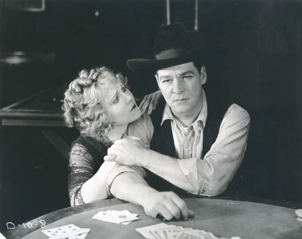 Scene still with William Russell as Bill Lark and Louise Lovely as Little Casino seated at a poker table in the 1920 Fox production <i>The Twins of Suffering Creek.</i>

From the original caption:
"What man is there among you would hesitate for even a moment against the pleadings of this beautiful girl?..."