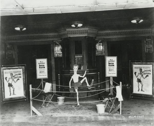 A boxing ring lobby display at the Empire Theatre for <i>Battling Butler</i> with Buster Keaton. The lobby cards read, "It's a knockout. Buster Keaton in 'Battling Butler.' 7 furious laugh rounds."