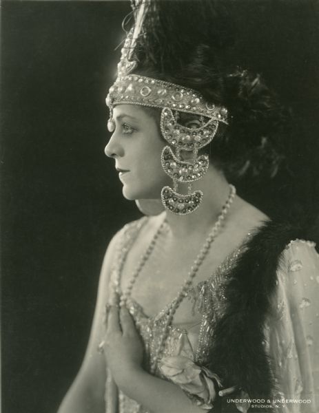 Waist-up publicity still of Valeska Suratt wearing a jeweled headdress, c. 1916.  A stamp on the back of the print reads: William Fox presents VALESKA SURATT in photo plays supreme released through FOX FILM CORPORATION.