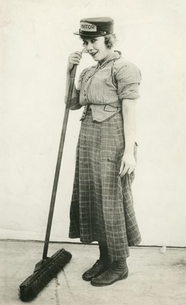 Publicity still of Louise Fazenda with broom and janitor's hat.