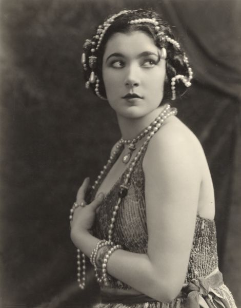 Waist-up seated portrait of Nita Naldi wearing pearls around her neck and in her hair. The photograph was made by Donald Biddle Keyes, most probably for the Paramount feature <i>Blood and Sand.</i>