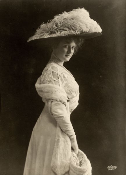 Three-quarter length portrait of Billie Burke distributed as publicity for the 1909 Broadway comedy <i>Love Watches</i>. This Sarony Studio portrait is a side view emphasizing Burke's hourglass figure.
