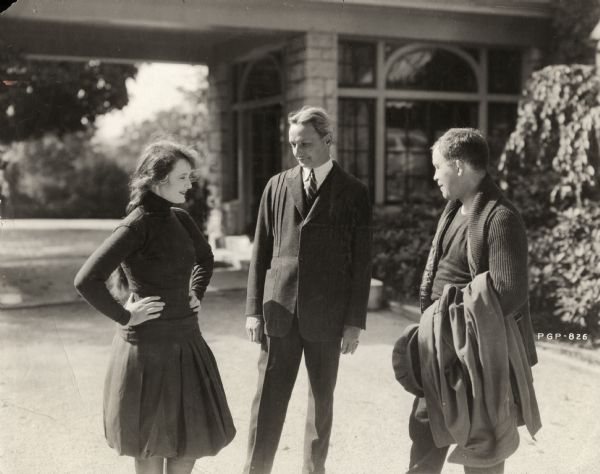 Billie Burke, Florenz Ziegfeld, and Kid Broad outside having a conversation. Burke has on athletic wear, bloomers and a sweater. This picture may have been taken to promote the 1919 Famous Players-Lasky film <i>Wanted-A Husband</i> in which both Billie Burke and Kid Broad, a former boxer, appeared.

Original caption:
"Billie Burke, her husband, Flo Ziegfeld, and Kid Broad, ex-pugilist."