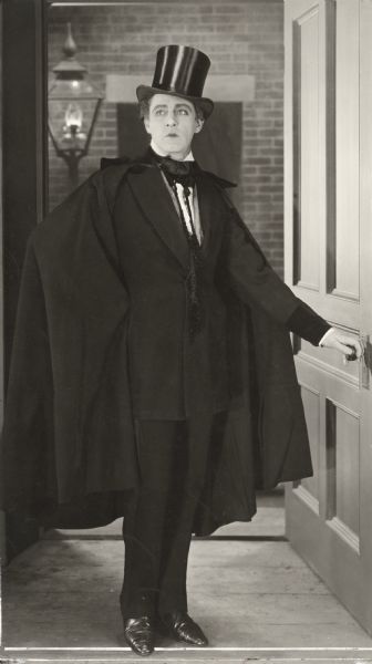 A very handsome John Barrymore in top hat and cape, as Dr. Henry Jekyll, in a full-length publicity still from <i>Dr. Jekyll and Mr. Hyde</i> (Famous Players-Lasky, 1920).