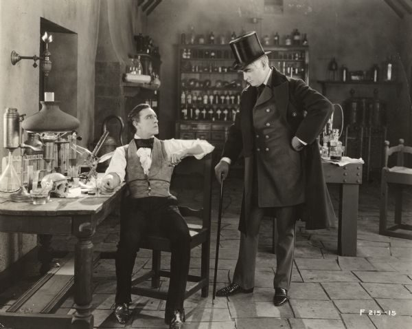 Dr. Henry Jekyll (played by John Barrymore) is confronted by Sir George Carew (Brandon Hurst) in Jekyll's laboratory in the Famous Players-Lasky Corporation 1920 production of <i>Dr. Jekyll and Mr. Hyde.</i>