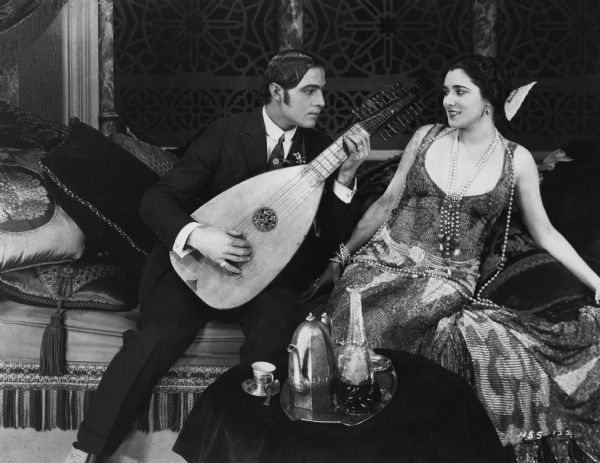 Juan Gallardo (played by Rudolph Valentino) plays the lute for Doña Sol de Guevara (Nita Naldi) in the 1922 Famous Players-Lasky production <i>Blood and Sand.</i>