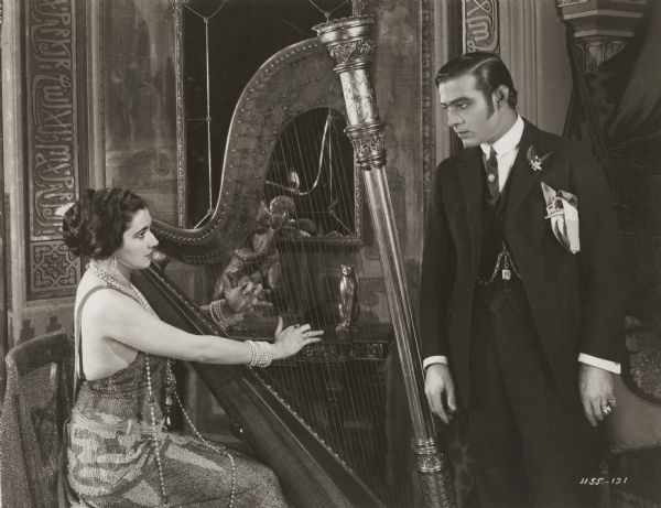 Doña Sol de Guevara (played by Nita Naldi) plays the harp for Juan Gallardo (Rudolph Valentino) in the 1922 Famous Players-Lasky production <i>Blood and Sand.</i>