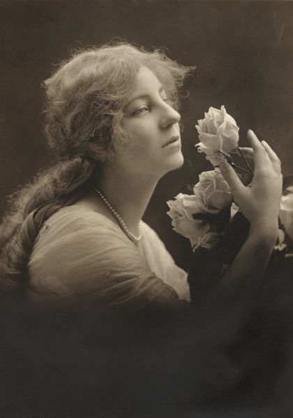 Head and shoulders portrait of Louise Vale holding roses, by the White Studio of New York. She was a silent film actress who died from the Spanish Flu in Madison, Wisconsin, during the influenza pandemic of 1918.