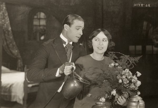 Rudolph Valentino, playing Juliantino Visconti, interrupts Dorothy Phillips, as Aurora Meredith, as she is putting a bouquet of roses in a vase, in the 1920 Universal production <i>Once to Every Woman,</i> a lost film.