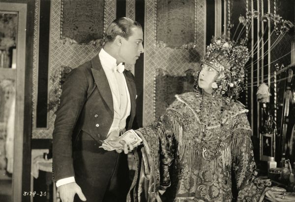 Rudolph Valentino, playing Juliantino Visconti, is offered money by Dorothy Phillips, as Aurora Meredith, wearig an elaborate oriental costume in the 1920 Universal production <i>Once to Every Woman,</i> a lost film.
