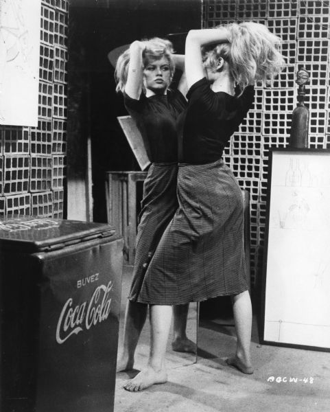 Publicity still of Brigitte Bardot as Juliette barefoot in front of a mirror in Roger Vadim's <i>Et Dieu ... créa la femme (And God Created Woman,</i> 1956).