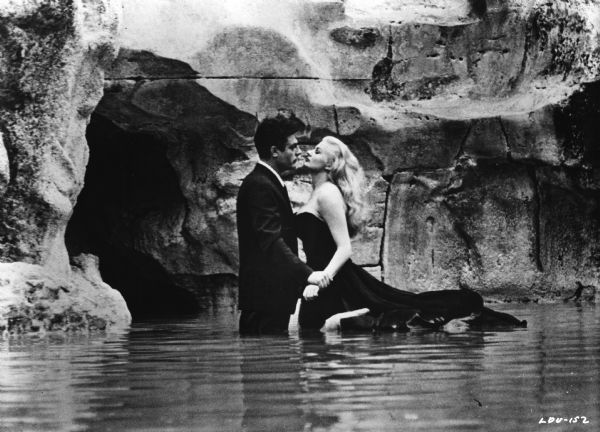 Marcello Mastroianni, as the newspaperman Marcello Rubini, and Anita Ekberg, as Sylvie a Hollywood star, stand thigh-deep in the Trevi Fountain in Rome in Federico Fellini's <i>La Dolce Vita</i> (1960).