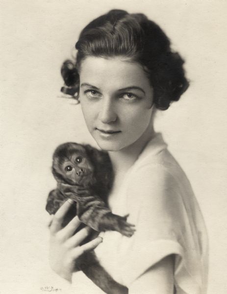 Quarter-length portrait of Irene Castle holding her pet monkey Rastus.