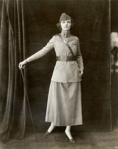 Original caption: "Mrs. Vernon Castle In her 'preparedness suit.' This is made on strictly mannish lines, and has no trimming whatever. She is shown here wearing the emblem of the British Royal Flying Corps, which was sent her by her husband, who is an aviator in this division. The suit is of covert tan cloth."