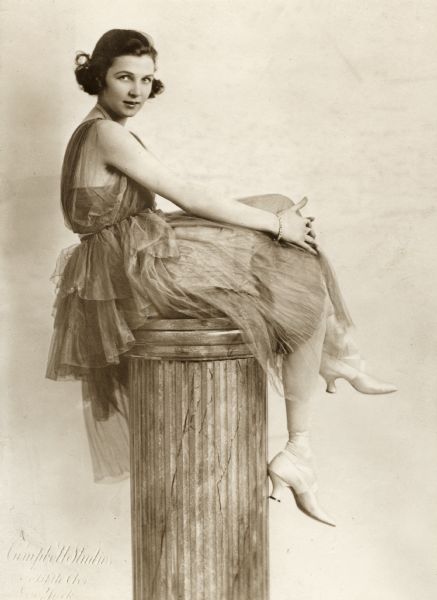 Publicity photograph of Irene Castle in a gauzy dress sitting on top of a column.