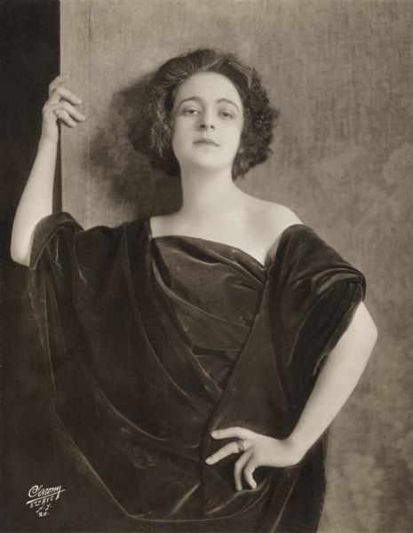 Waist-up studio portrait of the French singer Suzanne Caubet wearing black velvet at the beginning of her American career.