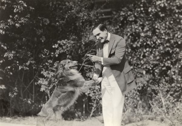 Vitagraph silent film star Earle Williams wags his finger at a collie.
