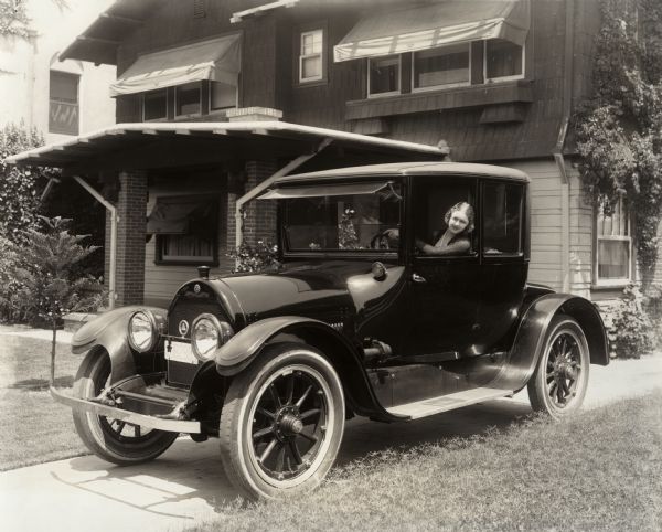 Silent film actress Vivian Martin sits behind the wheel of what appears to be a 1916 Cadillac two-door coupe.
